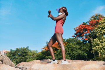 Wall Mural - Young woman exercising outdoors on rocks under a blue sky