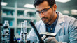 © Jahid - Male Chemist. Serious scientist looking at test tube in laboratory. Young man in eyeglasses holding test tube while working in chemical laboratory