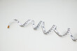 © ADDICTIVE STOCK - Top view of a curled measuring tape on a white background