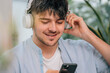© carballo - young man at home with headphones and mobile phone