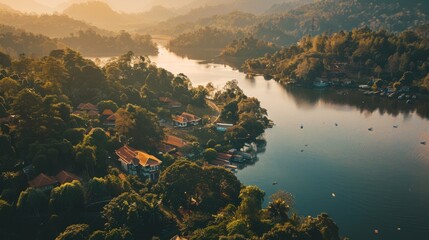 Poster - An aerial view of a tranquil lakeside village surrounded by lush, sunlit woodlands and a river winding through the serene scene.