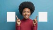 © Tatiana - A pleased dark-skinned woman with an Afro hairstyle, pointing with both forefingers to empty space for your promotion, against a blue background.