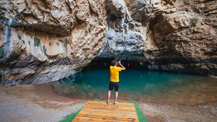 A tourist photographing the beauty of Altinbesik Cave. The tourist takes photos of the surroundings with his camera in hand. Antalya, Turkey.