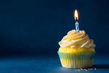 Wall Mural - yellow birthday cupcake with burning candle and blue background