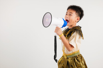 Portrait Thailand kid boy smiling traditional Thai dress costume shouting by megaphone, studio shot isolated white background, primary screeching through in megaphone announces discounts