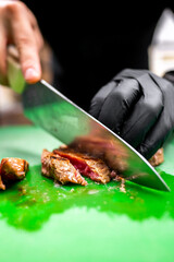 Sticker - A close-up of a hand in a black glove slicing cooked tuna on a green cutting board with a large chef’s knife. The focus is on the action of cutting, highlighting culinary skills and food preparation.