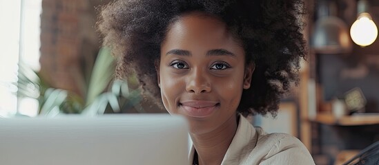 Leinwandbilder - Smiling young Black businesswoman at modern office in online meeting looking at laptop screen with copy space image