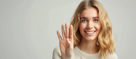 Sticker - Friendly pretty blonde woman smiling holding up five fingers in a countdown style gesture against a copy space image