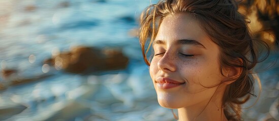 Wall Mural - A serene young woman enjoying by the sea with closed eyes smiling relaxation concept portraying beauty Copy space image available