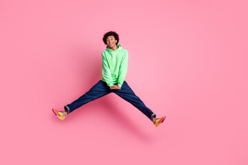 Poster - Full body portrait of cool young man jump empty space wear green hoodie isolated on pink color background