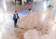 © Vasil - A bride and groom are walking down a dance floor with fireworks in the background. The bride is wearing a long white dress and the groom is wearing a suit. Scene is celebratory and romantic