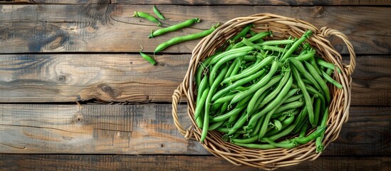 Poster - Top view of a cane basket with freshly picked green French beans on a wooden surface with room for a separate image alongside. Creative banner. Copyspace image