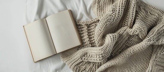 Poster - A book and a sweater set against a white backdrop creating a simple composition with copy space for an image