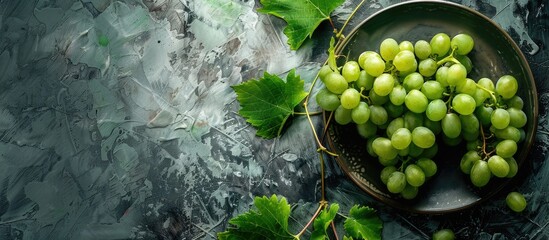 Wall Mural - Plate with juicy green grapes and foliage on weathered grunge background perfect as a copy space image