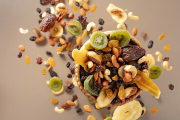 Wall Mural - Dried tropical fruits with various nuts and raisins on a beige background.