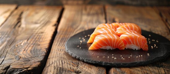 Aufkleber - A display of fresh salmon sashimi on a black stone plate atop a wooden table featuring a background with sufficient copy space for Japanese cuisine