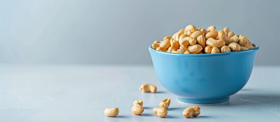 Wall Mural - A blue bowl filled with roasted peanuts on a white background with copy space image