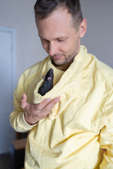 Wall Mural - Young Caucasian man plays with cute rat at home, adorable home pet.