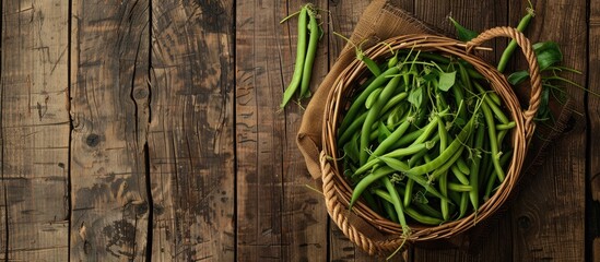 Poster - Top view of a rustic wooden surface adorned with a cane basket filled with freshly picked green French beans creating a picturesque scene with ample copy space image