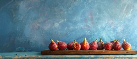 Poster - Ripe fresh figs arranged on a wooden board against a grunge blue backdrop with copy space image