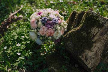 Wall Mural - A bouquet of flowers is placed on top of a mossy log. The flowers are a mix of pink and purple, and they are arranged in a way that makes them look like they are blooming. The log is covered in moss