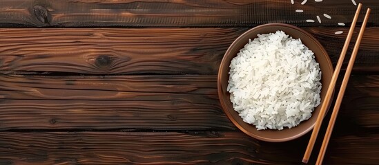 Aufkleber - A delicious bowl of cooked rice with chopsticks on a wooden table suitable for adding text in the empty area of the image. Creative banner. Copyspace image