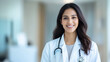 © Iana - Portrait of  Asian Indian female woman doctor in white coat with stethoscope smiling clinic hospital background