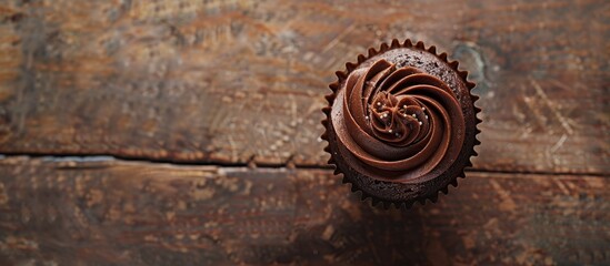 Poster - A delectable chocolate cupcake sits on a rustic table with copy space in a top view food background