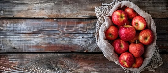 Poster - Top view of a wooden background holding freshly arranged red apples in a grid bag perfect for a copy space image