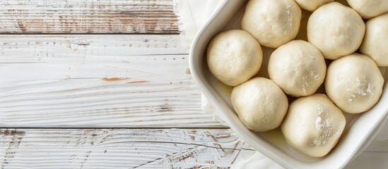 Poster - Top down view of scrumptious dough balls in a baking dish on a white wooden surface with ample space for text beside the image