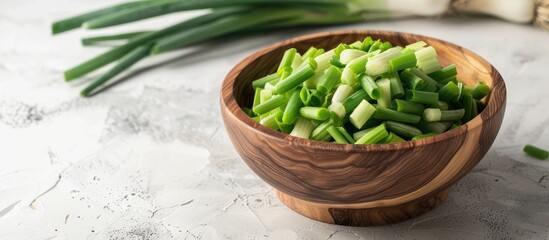 Aufkleber - A wooden bowl holds chopped spring onions on a white table providing ample copy space in the image