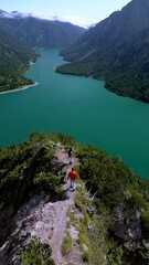 Wall Mural - Plansee Austria,Experience the breathtaking and stunning view of a beautiful tranquil lake peacefully nestled amid majestic mountains, a couple of man and woman hiking a mountain in Austria