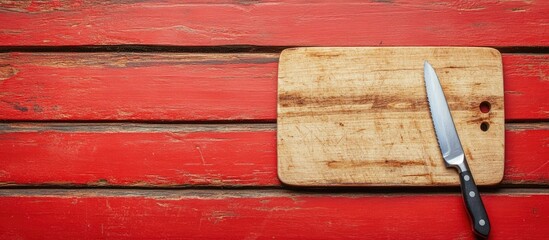 Poster - Empty cutting board and knife on a red wooden table for showcasing products Top view. with copy space image. Place for adding text or design