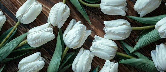 Bright white artificial tulip crafted from plastic positioned on a tile floor with a dark brown wood pattern. with copy space image. Place for adding text or design