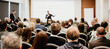 © kasto - Speaker giving a talk in conference hall at business event. Rear view of unrecognizable people in audience at the conference hall. Business and entrepreneurship concept