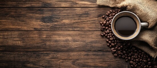 Wall Mural - a warm cup of coffee with a sack beside coffee beans on a wooden background. with copy space image. Place for adding text or design