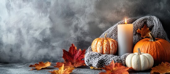 Poster - Autumn arrangement A frame created from a knitted plaid or scarf along with a candle fallen leaves and pumpkins on a grey background Autumn fall banner sale story concept Side view copyspace