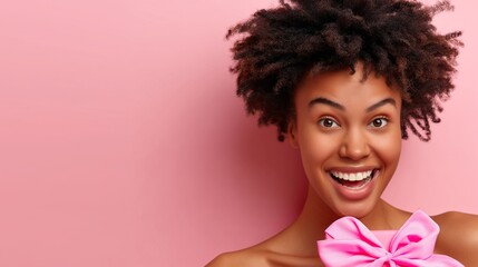 Wall Mural - A woman with curly hair is smiling and holding a pink bow. Concept of joy and celebration, as the woman is happy and excited about the bow