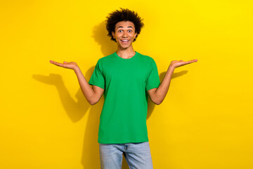 Sticker - Photo of cheerful positive guy dressed green t-shirt comparing arms emtpy space isolated yellow color background