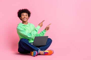 Poster - Full body portrait of cool young man laptop direct fingers empty space wear green hoodie isolated on pink color background