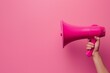 © srenhouse - A hand holding a megaphone on a pink background
