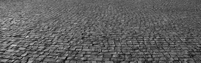 Old square cobble stone with green grass. paving perspective background.Paving stone pavement texture. Cobblestone pavement. stone sidewalk. texture. Cobble stone road cobble texture.  perspective