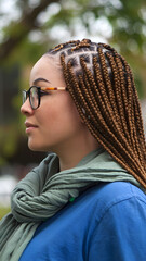 Wall Mural - A profile portrait of a beautiful black woman with long braided hair, showcasing her elegant features and glowing skin. The background is blurred.