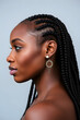 © Janos - A profile portrait of a beautiful black woman with long braided hair, showcasing her elegant features and glowing skin. The background is blurred.