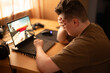 © Svetlana - A young man is at home playing a computer game on his laptop. He is losing and covers his face with his hand.