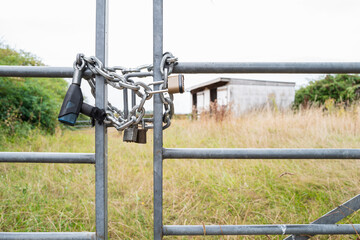 Shallow focus of a locked farm and paddock gate which has been subject to rural crime. Stout padlocks and chains can be seen to help deter thieves in the area.