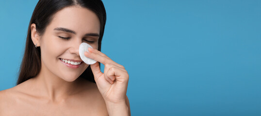 Poster - Young woman with cotton pad on light blue background. Banner design with space for text