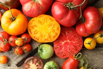 different ripe tomatoes on wooden table, top view