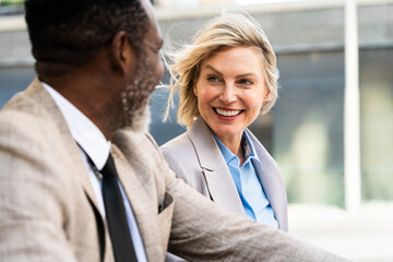 Mauture black businessman and middle aged businesswoman talking on an business meeting, close-up on smiling mature corporate woman's face