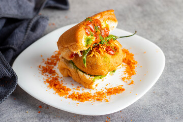 selective focus of Mumbai's famous street food delicious Vada Pav, With coriander leave chutney, tomato sauce, dry garlic chutney and fried chilli. 